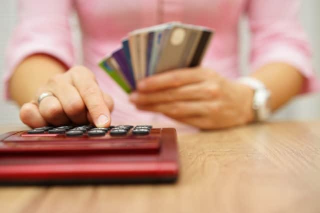 Calculator, credit cards, person holding credit cards